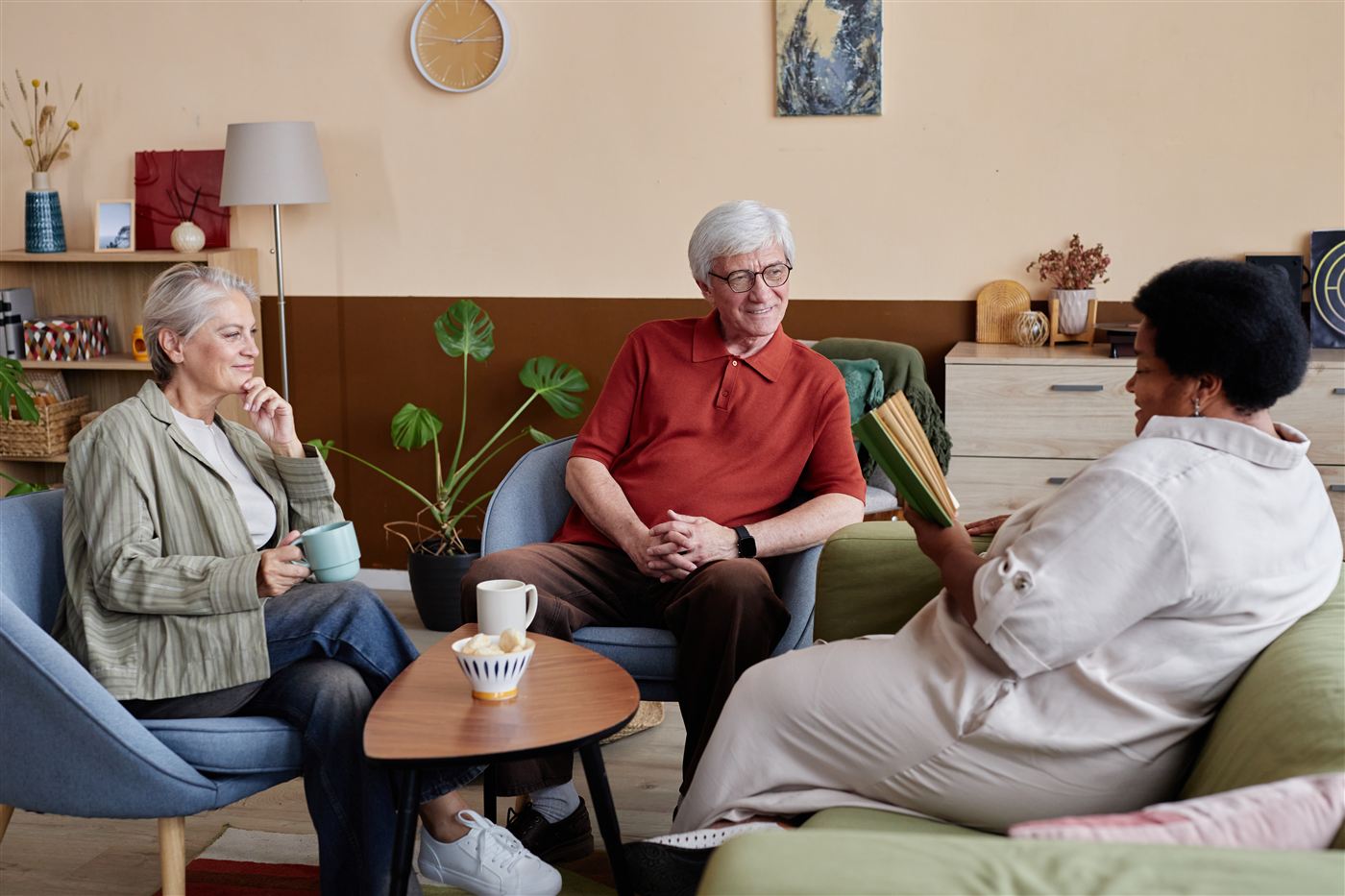 Residents relaxing and chatting together in a sunny senior living common room.